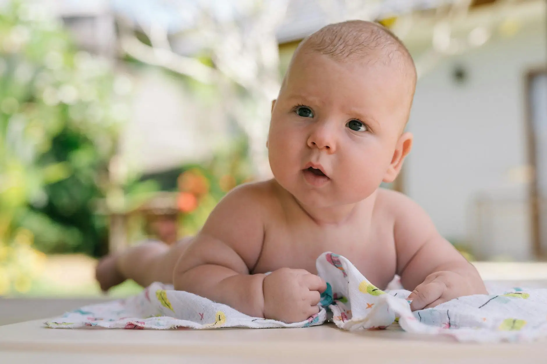 Gambar ilustrasi bayi mengalami perut kembung dengan latar belakang bunga chamomile dan daun peppermint yang dapat membantu mengatasi masalah kesehatan tersebut secara alami